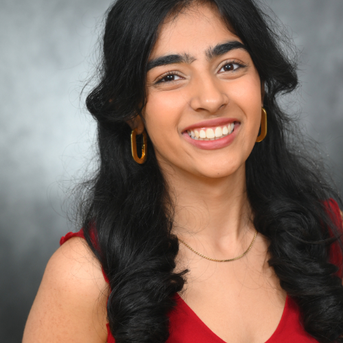 Smiling woman in red top with gold jewelry.