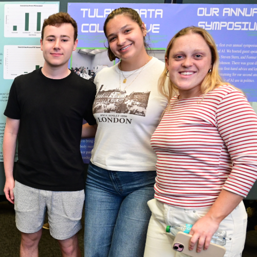 Three students pose in front of a research poster